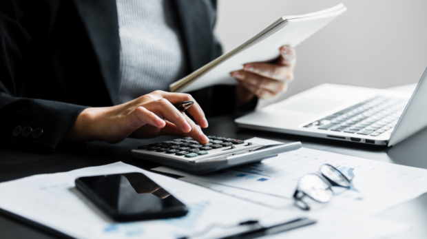 Close up of businesswomen or accountant using calculator calculate while working analytic business report on the workplace, Planning financial and accounting concept.