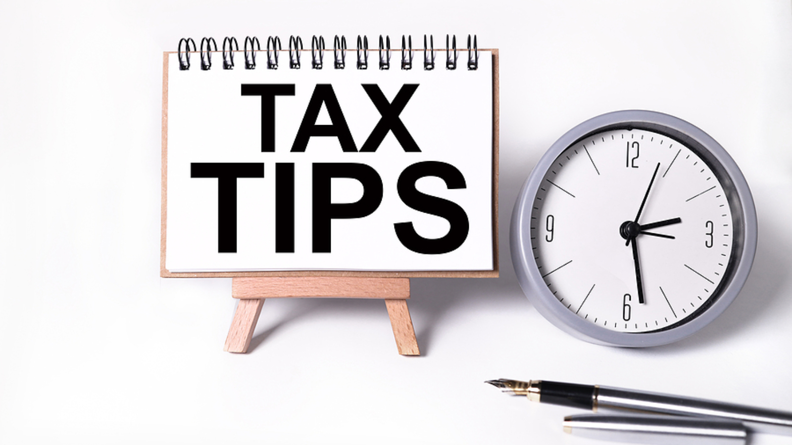 TAX TIPS. text on white notepad paper on white background. near the table clock