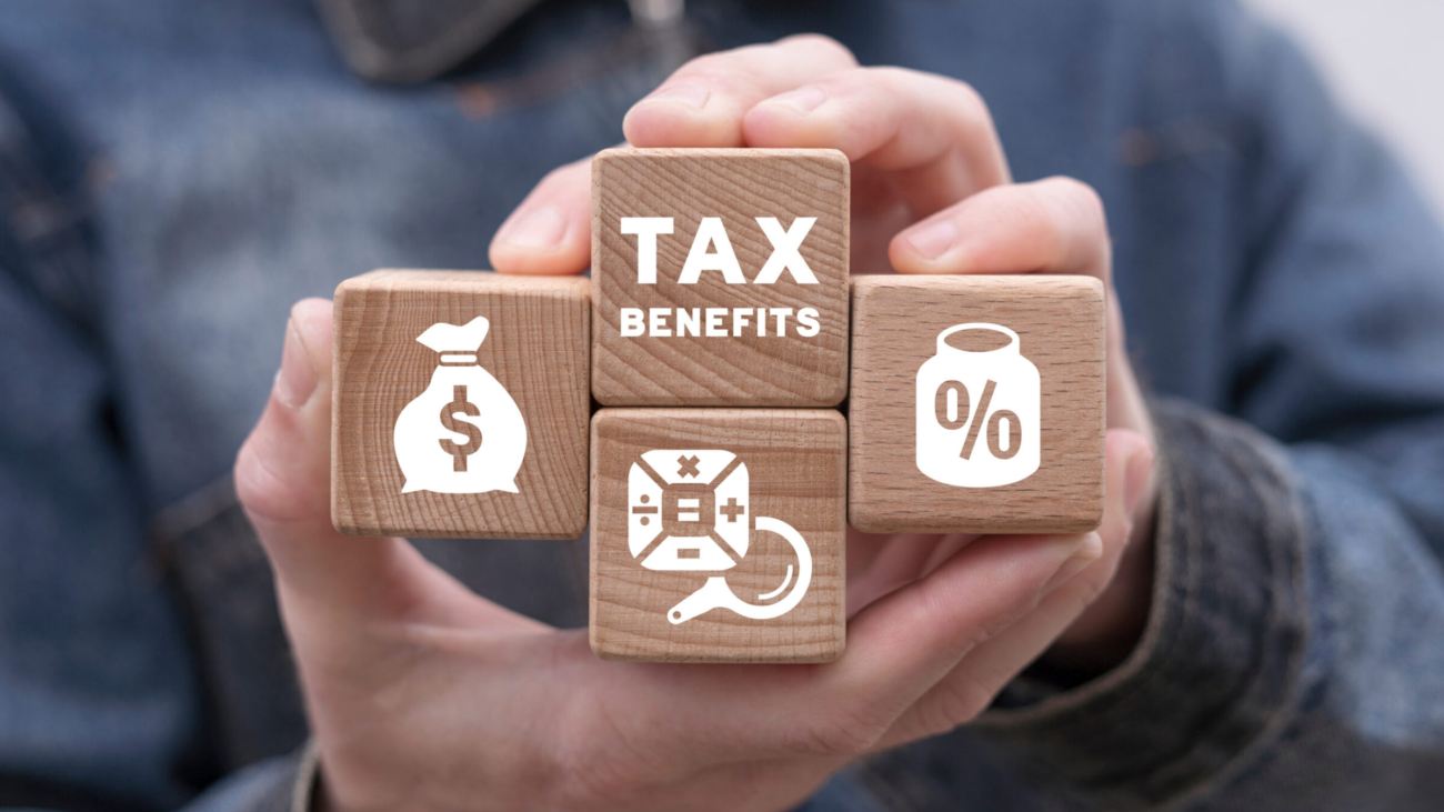 Man holding wooden blocks with icons and  sees inscription: TAX BENEFITS. Concept of tax benefits of accounting. Time to pay tax in year. Business, finance, banking and planning budget.