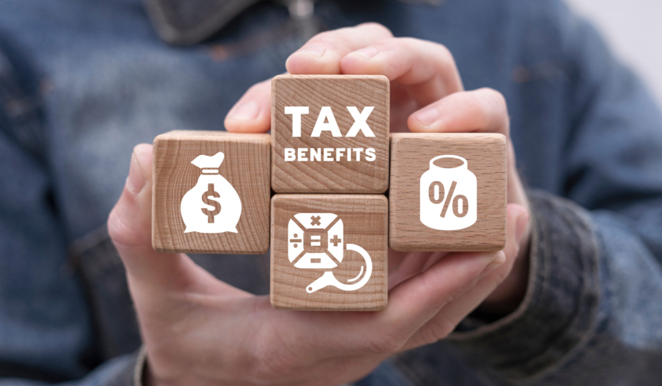 Man holding wooden blocks with icons and  sees inscription: TAX BENEFITS. Concept of tax benefits of accounting. Time to pay tax in year. Business, finance, banking and planning budget.