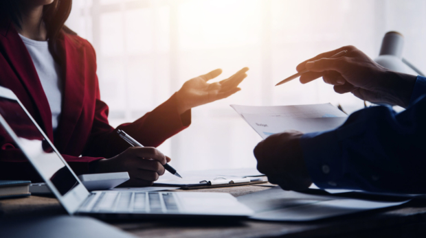 Financial analysts analyze business financial reports on a digital tablet planning investment project during a discussion at a meeting of corporate showing the results of their successful teamwork.