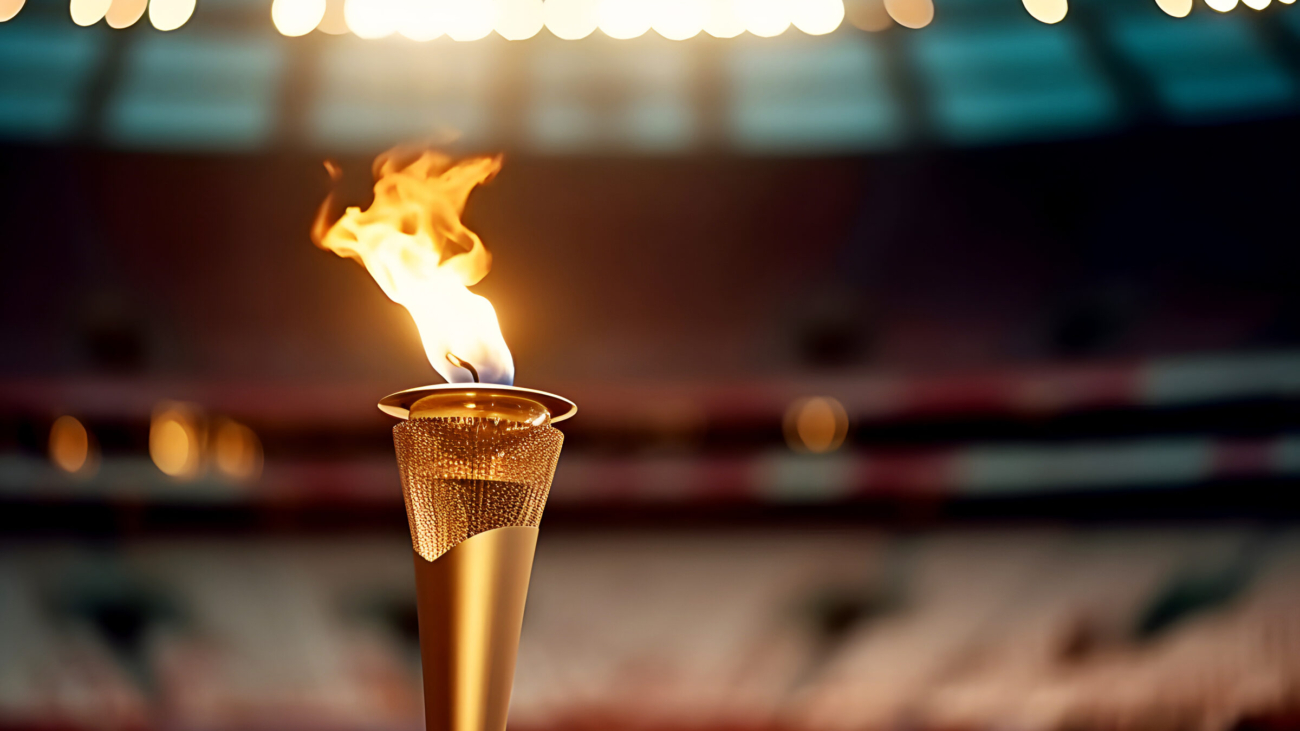Flame burns in Olympic torch against blurred background of sports arena on eve of opening of Olympic Games.