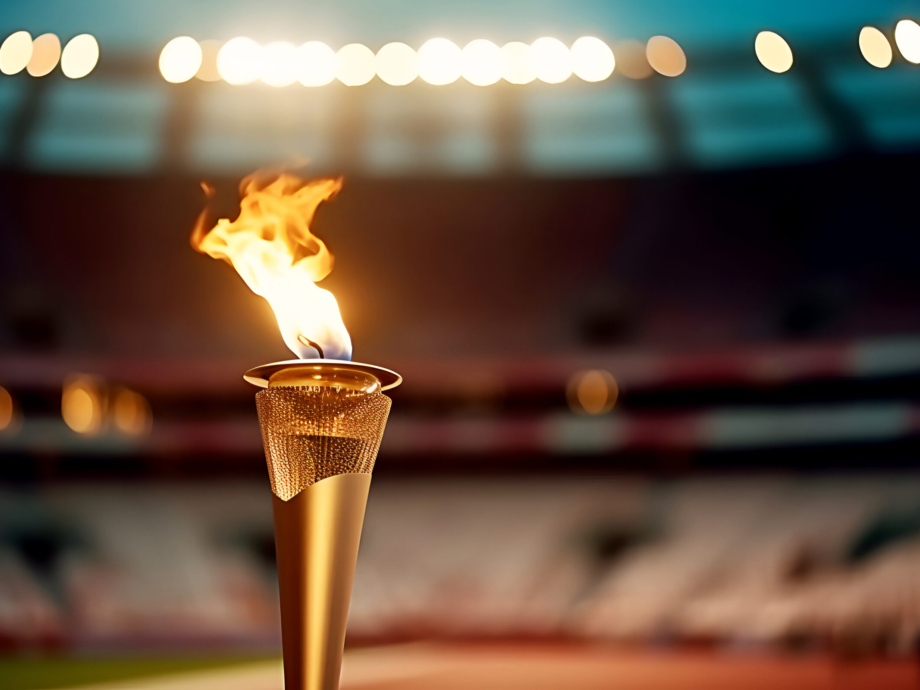 Flame burns in Olympic torch against blurred background of sports arena on eve of opening of Olympic Games.